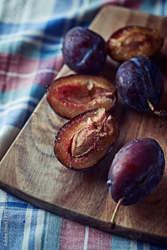 Photo: Whole and halved plums on a kitchen board Whole and halved plums on a kitchen board