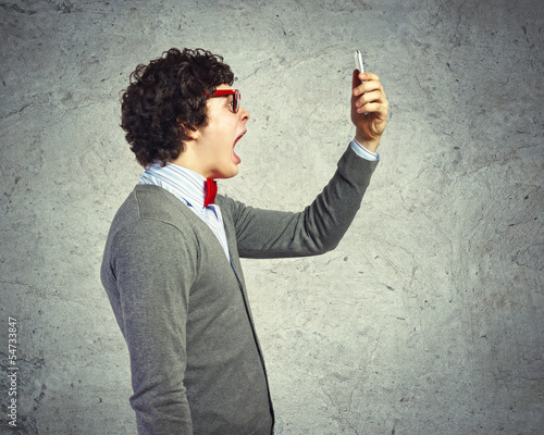 Photo: Young man shouting at his mobile phone Young man shouting at his mobile phone