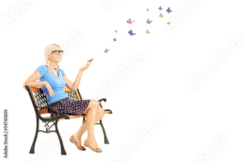 Photo: Young female sitting on a wooden bench and looking at colorful b Young female sitting on a wooden bench and looking at colorful b