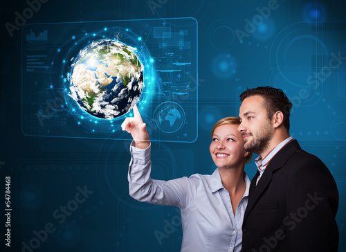 Photo: Young couple touching high-tech 3d earth panel Young couple touching high-tech 3d earth panel
