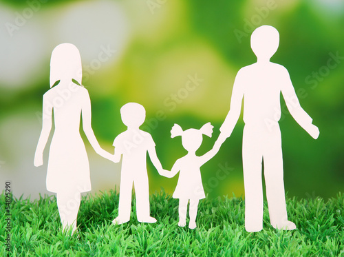 Photo: Family from paper on grass on bright background Family from paper on grass on bright background