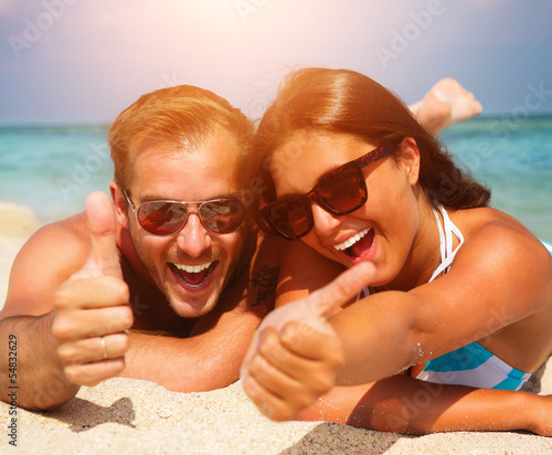 Photo: Happy Couple in Sunglasses having fun on the Beach Happy Couple in Sunglasses having fun on the Beach