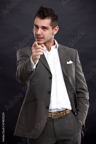 Photo: young business man pointing to the camera on black background young business man pointing to the camera on black background