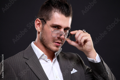 Photo: Young handsome man in black suit and glasses smiling Young handsome man in black suit and glasses smiling