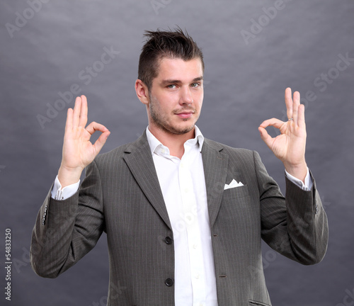 Photo: Happy smiling young business man with thumbs up gesture Happy smiling young business man with thumbs up gesture