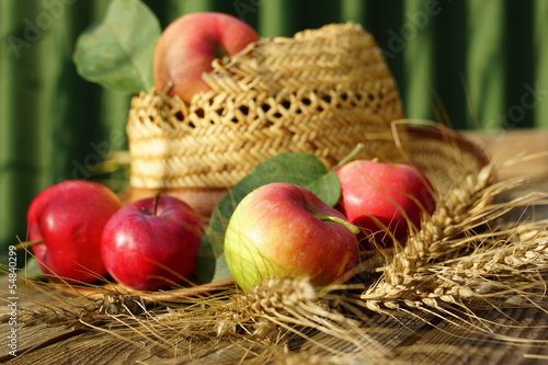 Photo: rural composition with apples, wheat and straw hat rural composition with apples, wheat and straw hat