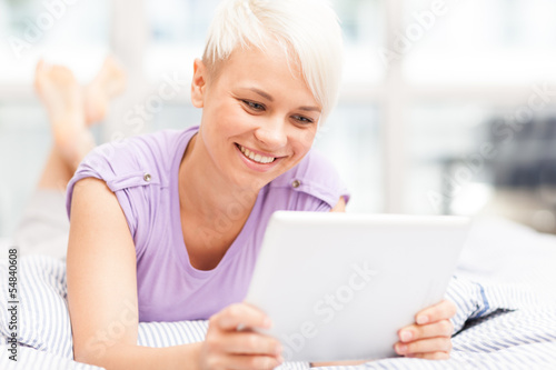 Photo: Smiling woman in the bed with tablet pc Smiling woman in the bed with tablet pc