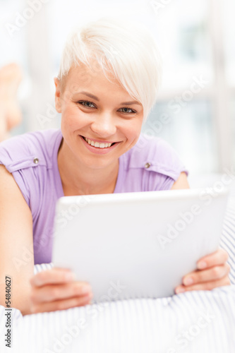 Photo: Smiling woman in the bed with tablet pc Smiling woman in the bed with tablet pc