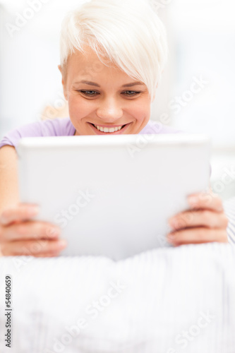Photo: Smiling woman in the bed with tablet pc Smiling woman in the bed with tablet pc