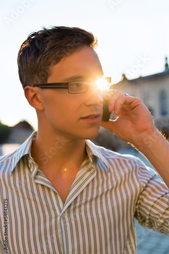 Photo: Man taking a call with mobile phone Man taking a call with mobile phone
