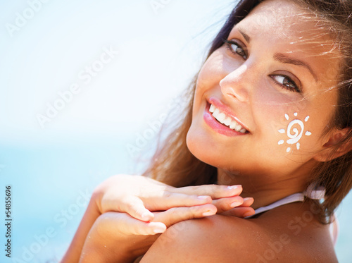 Photo: Beautiful happy Girl applying Sun Tan Cream on her Face Beautiful happy Girl applying Sun Tan Cream on her Face