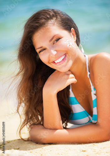 Photo: Beautiful happy Girl applying Sun Tan Cream on her Face Beautiful happy Girl applying Sun Tan Cream on her Face