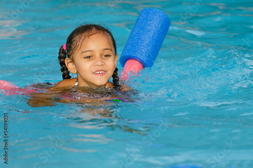 Photo: Pretty mixed race child swimming in pool during summer Pretty mixed race child swimming in pool during summer