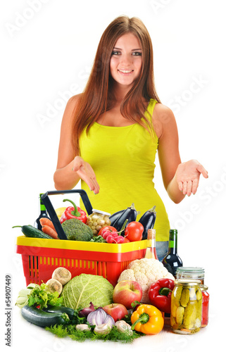 Photo: Young woman with assorted grocery products isolated on white Young woman with assorted grocery products isolated on white