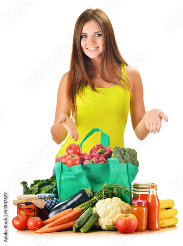 Photo: Young woman with variety of grocery products in shopping bag Young woman with variety of grocery products in shopping bag