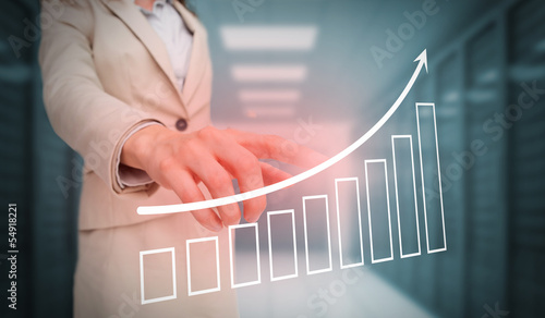 Photo: Businesswoman touching bar chart and arrow graphic Businesswoman touching bar chart and arrow graphic