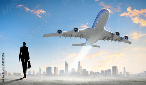 Photo: Business woman looking at airplane in sky Business woman looking at airplane in sky