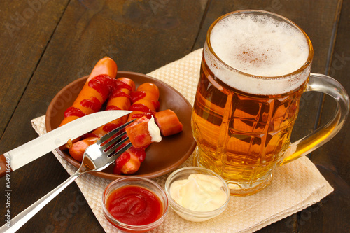 Photo: Beer and grilled sausages on wooden background Beer and grilled sausages on wooden background