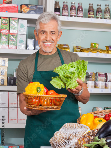 Photo: Senior Salesman Selling Vegetables In Store Senior Salesman Selling Vegetables In Store