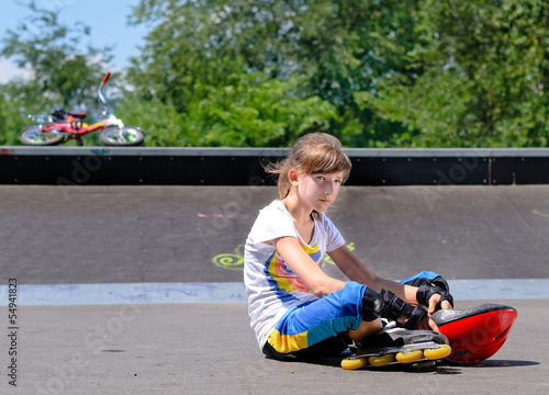 Photo: Girl with roller skates sitting lonely in the park Girl with roller skates sitting lonely in the park