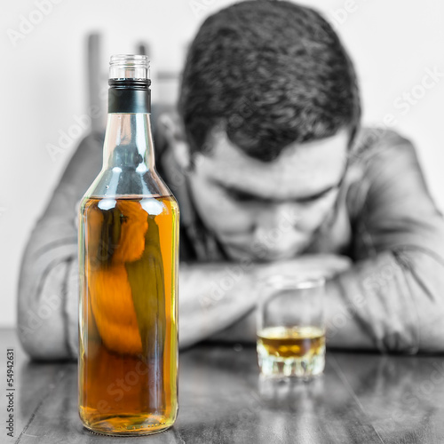 Photo: Whisky bottle with an out of focus drunk man Whisky bottle with an out of focus drunk man