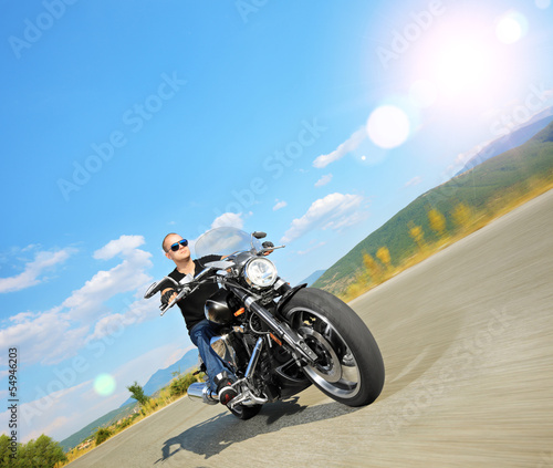 Photo: Biker riding a customized motorcycle on an open road Biker riding a customized motorcycle on an open road