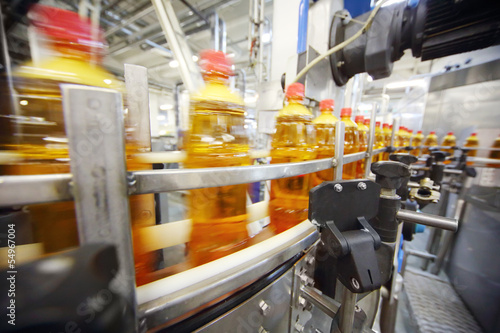 Photo: Yellow plastic bottles with light beer go on conveyor belt Yellow plastic bottles with light beer go on conveyor belt