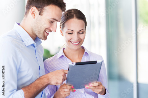 Photo: Business people using digital tablet together Business people using digital tablet together