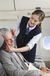 Photo: Deutschland, Bayern, München, junge Stewardess kümmert sich um Geschäftsmann in Business-Class-Flugzeugkabine Deutschland, Bayern, München, junge Stewardess kümmert sich um Geschäftsmann in Business-Class-Flugzeugkabine