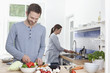 Photo: Deutschland, Bayern, München, Mann Hacken Zucchini in der Küche, Frau im Hintergrund Deutschland, Bayern, München, Mann Hacken Zucchini in der Küche, Frau im Hintergrund