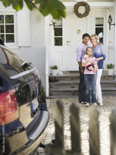 Photo: Familie mit Baby stehend vor dem Haus Familie mit Baby stehend vor dem Haus