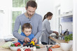 Photo: Deutschland, Bayern, München, Vater und Sohn hacken Pfeffer und Mutter im Hintergrund Deutschland, Bayern, München, Vater und Sohn hacken Pfeffer und Mutter im Hintergrund