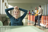Photo: Deutschland, Leipzig, Frau sitzt an einem Tisch im Flur, Studenten stehen im Hintergrund Deutschland, Leipzig, Frau sitzt an einem Tisch im Flur, Studenten stehen im Hintergrund