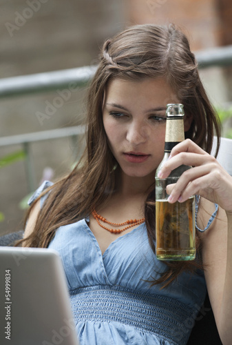 Photo: Deutschland, Berlin, Nahaufnahme der jungen Frau mit Laptop und Bierflasche Deutschland, Berlin, Nahaufnahme der jungen Frau mit Laptop und Bierflasche