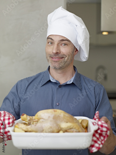 Photo: Deutschland, Köln, Erwachsene mit gebratenem Huhn, Lächeln Deutschland, Köln, Erwachsene mit gebratenem Huhn, Lächeln
