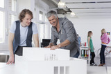 Photo : Deutschland, Bayern, München, Männer betrachten Architekturmodell im Büro, Kollegen im Hintergrund Deutschland, Bayern, München, Männer betrachten Architekturmodell im Büro, Kollegen im Hintergrund