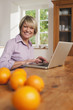 Photo: Deutschland, Kratzeburg, erwachsene Frau mit Laptop, Früchte auf dem Tisch im Vordergrund Deutschland, Kratzeburg, erwachsene Frau mit Laptop, Früchte auf dem Tisch im Vordergrund