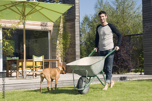 Photo: Junger Mann im Garten, drängen Schubkarre Junger Mann im Garten, drängen Schubkarre