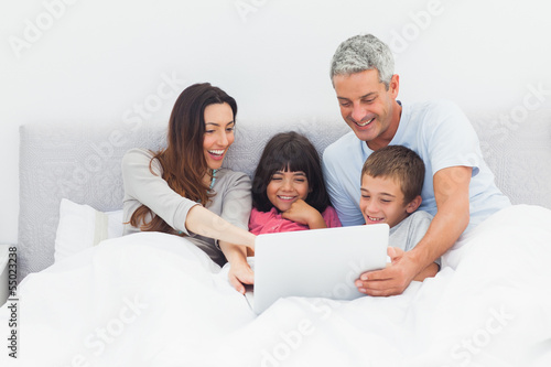 Photo: Family lying in bed using their laptop Family lying in bed using their laptop