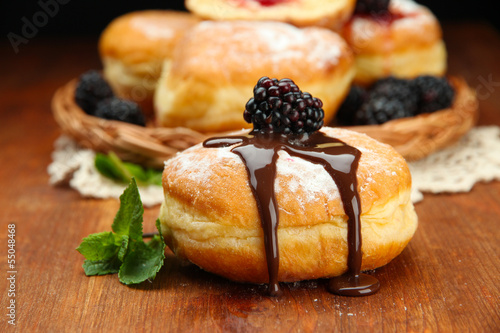 Photo: Tasty donuts with chocolate and berries on wooden table Tasty donuts with chocolate and berries on wooden table