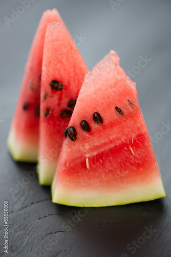 Photo: Slices of watermelon on black wooden background, vertical shot Slices of watermelon on black wooden background, vertical shot
