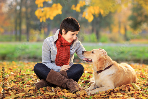 Photo: Young woman in a park stroking her dog Young woman in a park stroking her dog