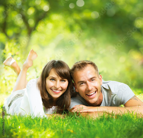 Photo: Happy Smiling Couple Together Relaxing on Green Grass Outdoor Happy Smiling Couple Together Relaxing on Green Grass Outdoor