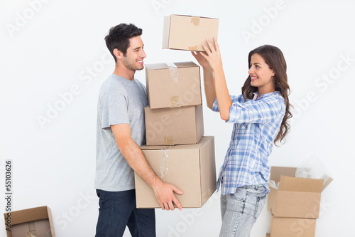 Photo: Woman giving boxes to her husband while they are moving Woman giving boxes to her husband while they are moving