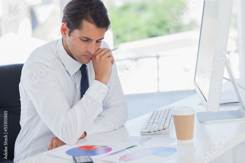 Photo: Concentrated businessman analyzing graphs Concentrated businessman analyzing graphs