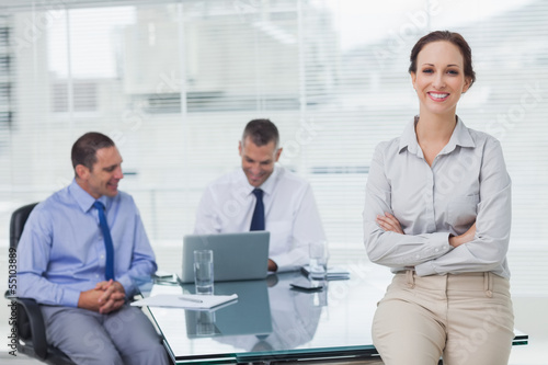 Photo: Happy businesswoman posing leaning against the desk Happy businesswoman posing leaning against the desk