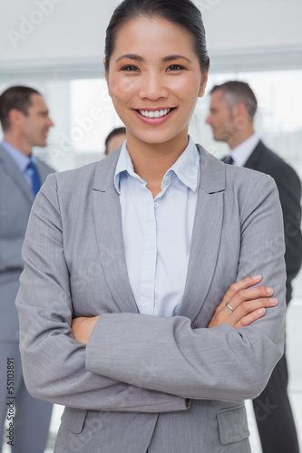 Photo: Businesswoman posing while colleagues talking together Businesswoman posing while colleagues talking together