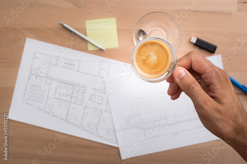 Photo: Hand holding a cup of coffee while working Hand holding a cup of coffee while working