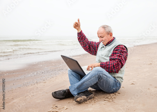 Photo: Old man with notebook on beach Old man with notebook on beach