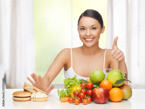 Photo: woman with fruits rejecting junk food woman with fruits rejecting junk food